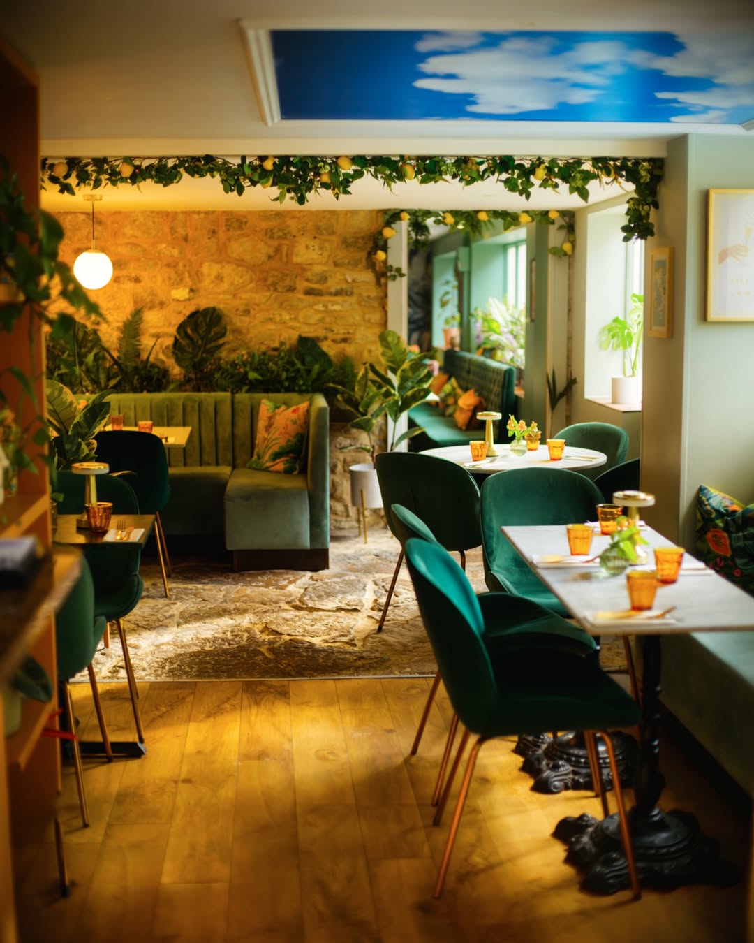 Italiano Vero&rsquo;s intimate dining room with green velvet seating, foliage and warm lighting